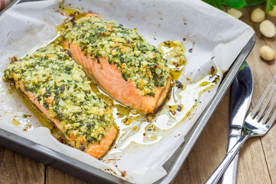 Frisches Lachsfilet mit Kartoffel-Pesto-Kruste aus dem Ofen angerichtet auf einem Blech