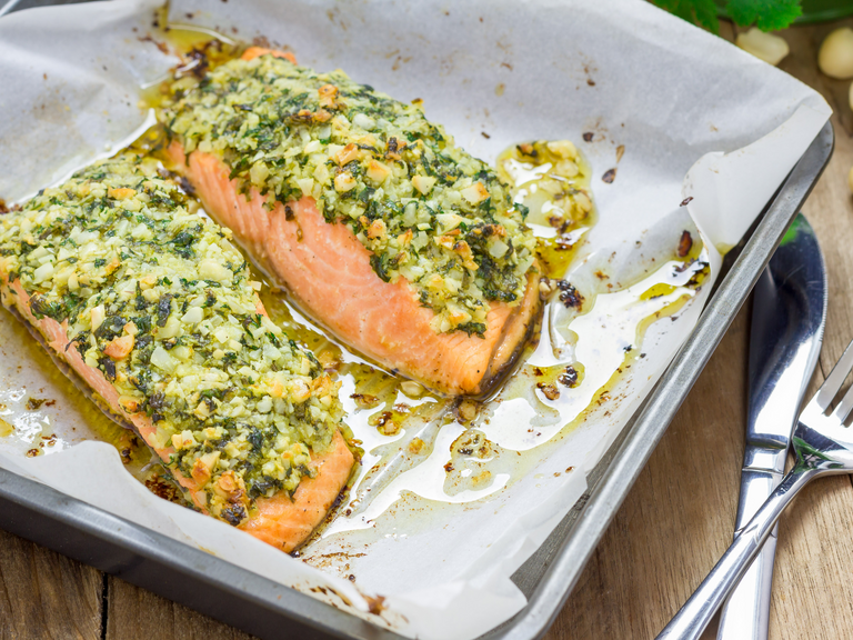 Lachsfilet mit Kartoffel-Pesto-Kruste frisch aus dem Ofen angereicht auf dem Backblech 